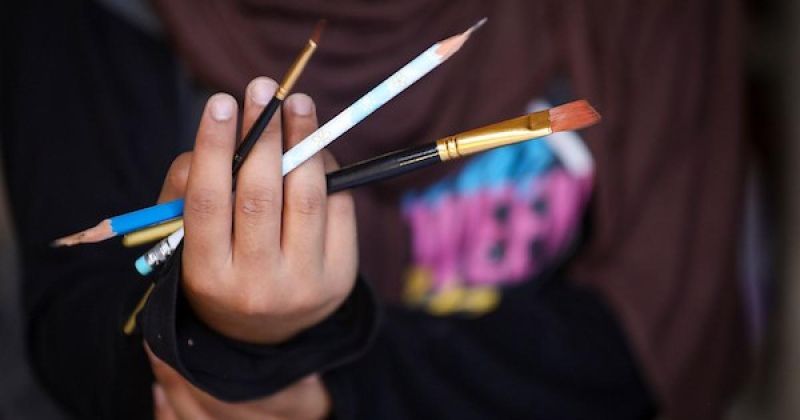 رغد حداد فتاة فلسطينية ترسم داخل خيمة للنازحين في حي الشيخ رضوان