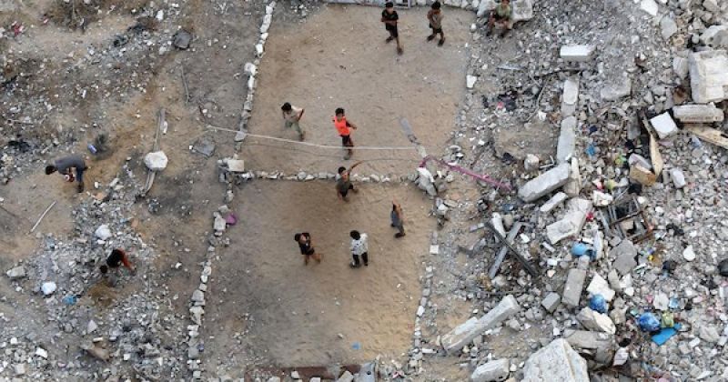أطفال فلسطينيون يلعبون الكرة الطائرة على ملعب أُقيم بين أنقاض المباني المدمرة