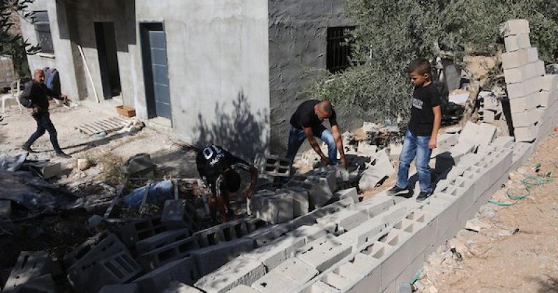 فلسطينيون يتفقدون منزلهم المدمر وأشجار الزيتون المحيطة به في قرية بورين